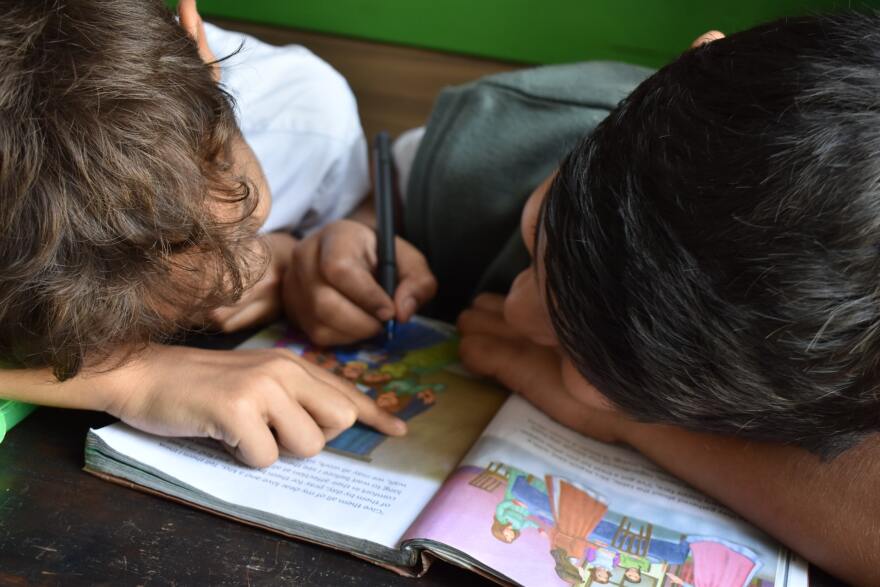 Young boys working on reading homework together. 