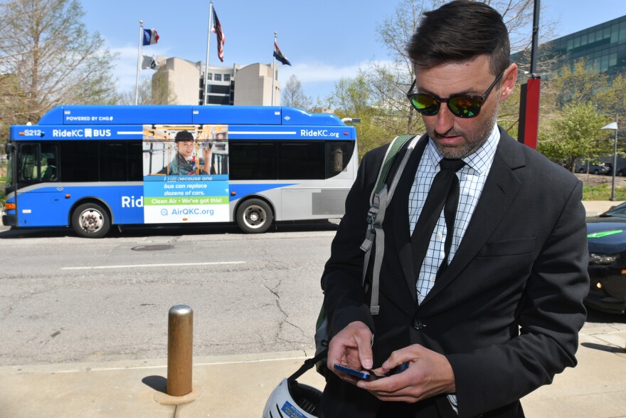 Eric Bunch scrolls through the Ride KC Transit app outside Kansas City City Hall.