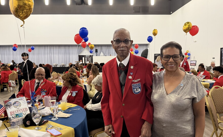 Daniel Keel, a 104-year-old Tuskegee veteran, poses with his daughter. He wears a red blazer. 