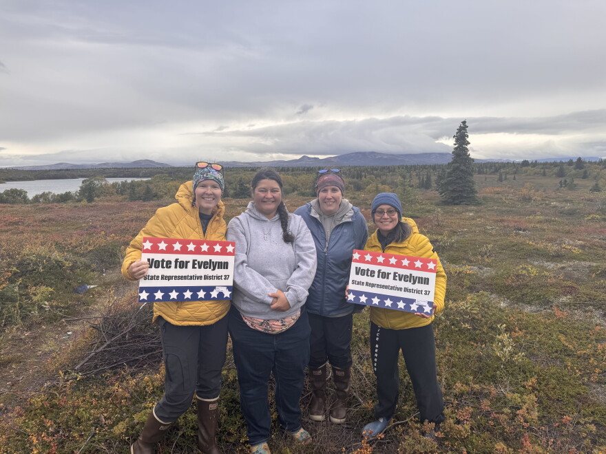 four women standing in a line against a natural background 