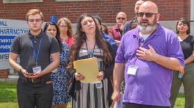 SEIU Local 580 President Matthew Gunnip, right, speaks at a press conference outside the Rhode Island Department of Behavioral Healthcare, Developmental Disabilities and Hospitals (BHDDH) brick office building in Cranston on July 1, 2025. He was joined by disability case managers who are calling on the state to raise their salaries and hire additional workers, including Alex Blue, far left, and Erica MacDougall, center front.
