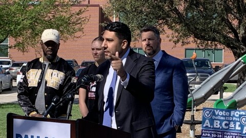 Man in blue suit at outdoor lectern with microphone