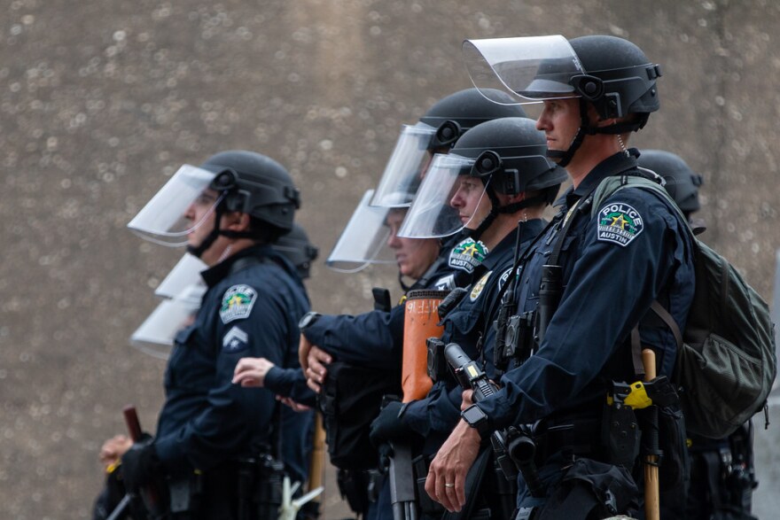 Austin police officers watch demonstrators outside APD headquarters on May 31.