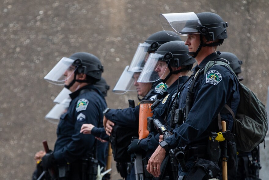 Austin police officers watch demonstrators outside APD headquarters on May 31. 