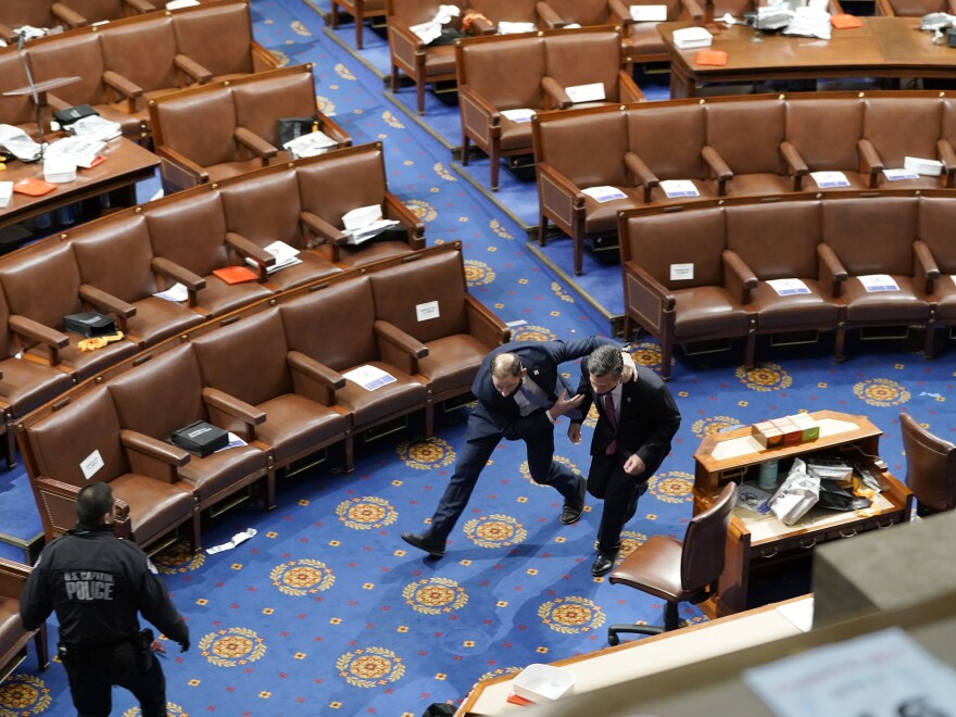 Members of Congress run for cover as rioters try to enter the House chamber on Jan. 6. At one point, rioters get near the Senate chamber, but a Capitol Police officer lures them away.