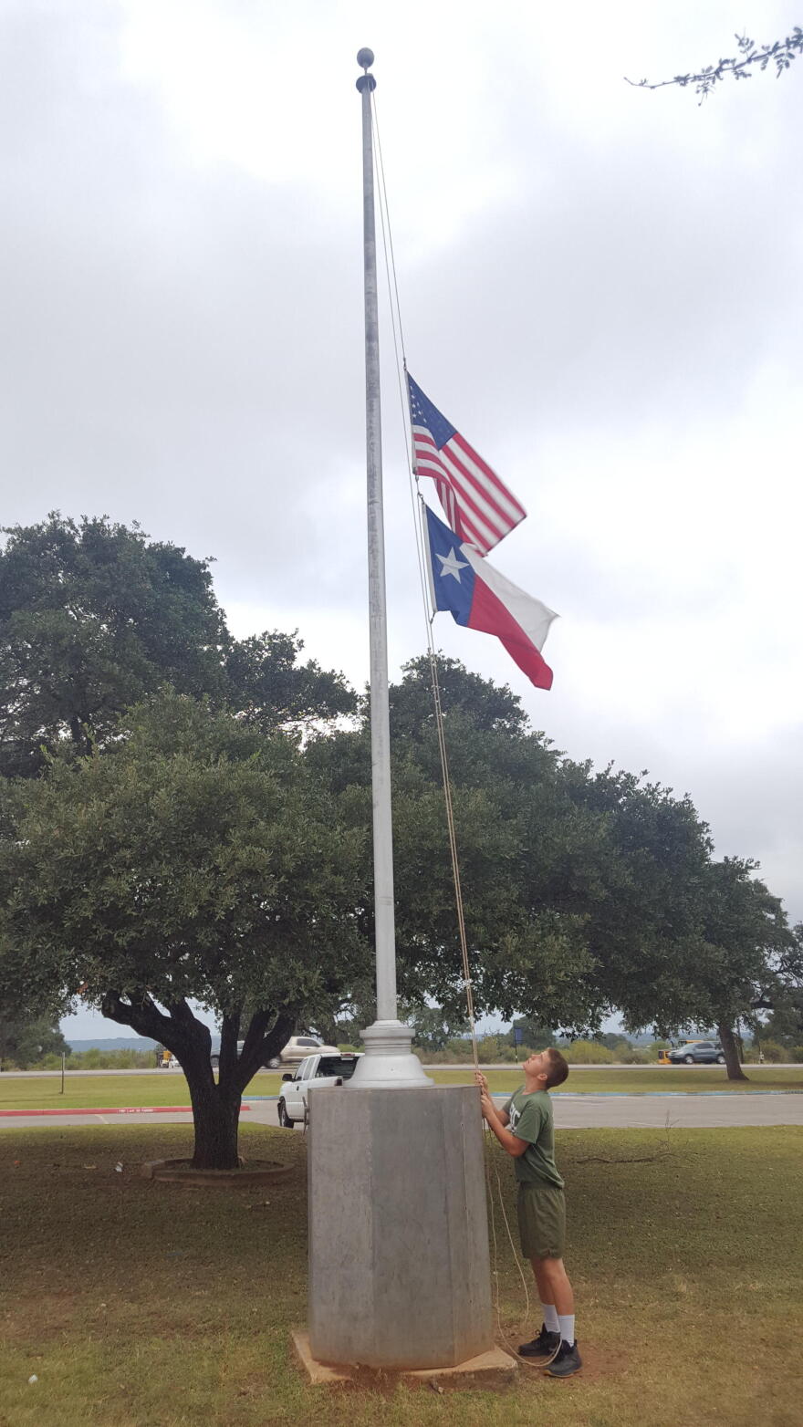 Matt Doerr lowers flags to half-staff at New Braunfels High School on Monday.
