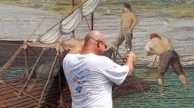 Herb Roe touches up a mural Saturday, near Limestone Landing in Maysville.