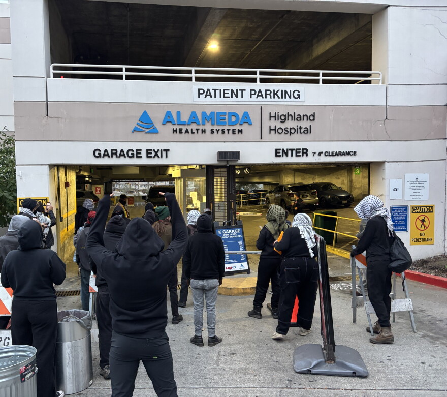 Protesters at Highland Hospital block an SUV from exiting the garage, which had been flagged as an ICE vehicle by community reporting networks.