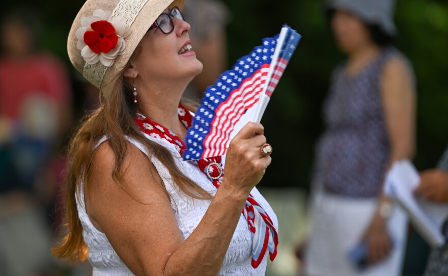 Miki Hossage wore red white and blue and carried an American Flag fan to battle the heat during a ceremony at the Wyoming Monument.