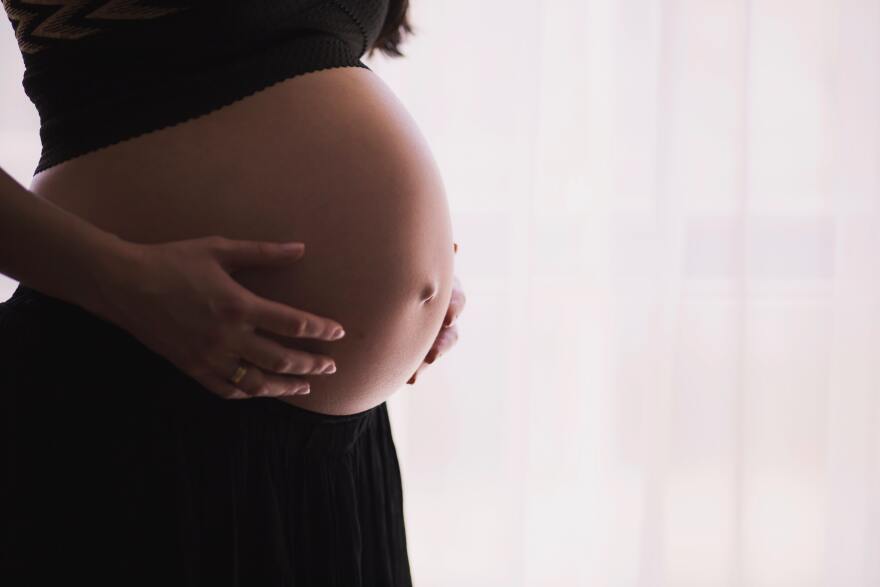 A pregnant person holds their stomach.