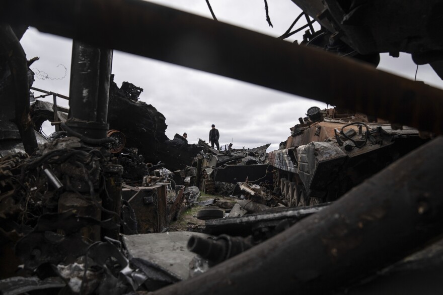 <strong>April 19:</strong> A man stands on top of destroyed Russian armored vehicles in Bucha.