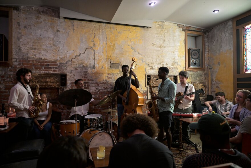 Aug. 1st, 2024 - Sunday Jazz members, Drummer Marcus Grant, Bassist Kweku Aggrey, Guitarist Dan Liparini, and Saxophonist Noah Campbell get ready to play with guest Saxophonist Alex Laurenzi, entering from the left side of the crowd. (Ayannah Brown/Connecticut Public)