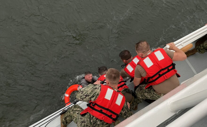 The crew of the Coast Guard Cutter Glenn Harris pulls a person from the water that was on the overturned commercial vessel off the coast of Louisiana.