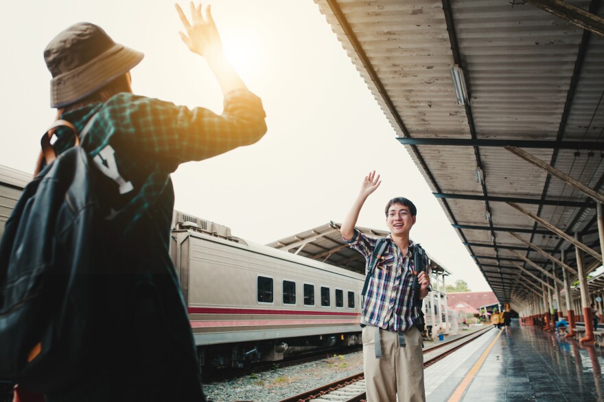 Two close friends waving hands, greet each other at train station.