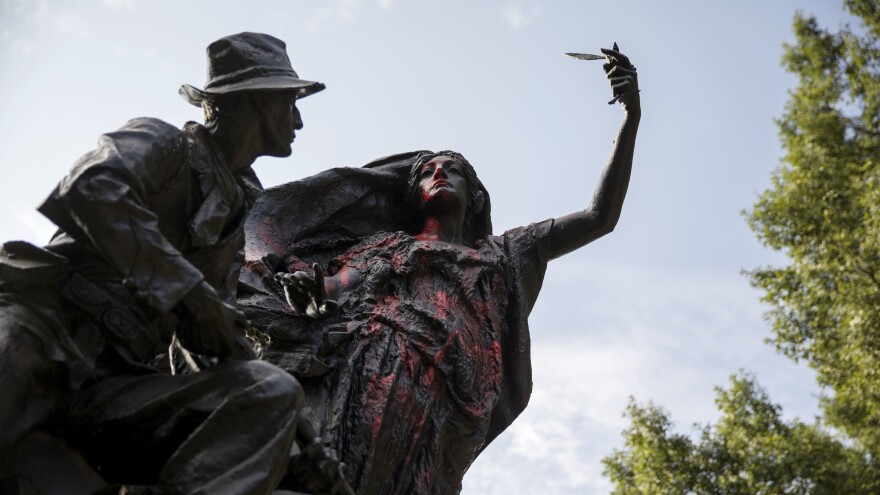 A statue of a Confederate soldier in Atlanta's Piedmont Park stands vandalized with spray paint on Monday. It was not the only Confederate monument to be vandalized in the wake of the violence in Charlottesville; a statue in Louisville, Ky., was splattered with paint too.