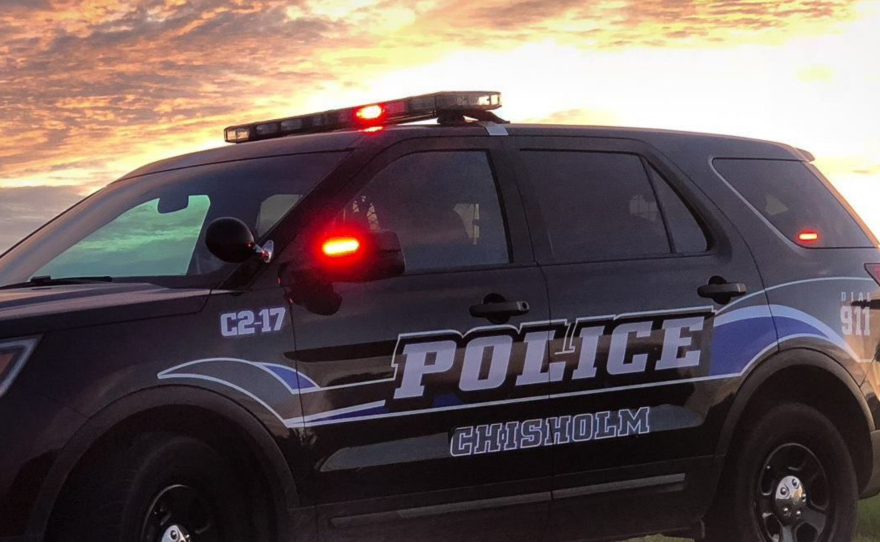 A Chisholm Police Department squad vehicle with its emergency lights engaged at dusk.