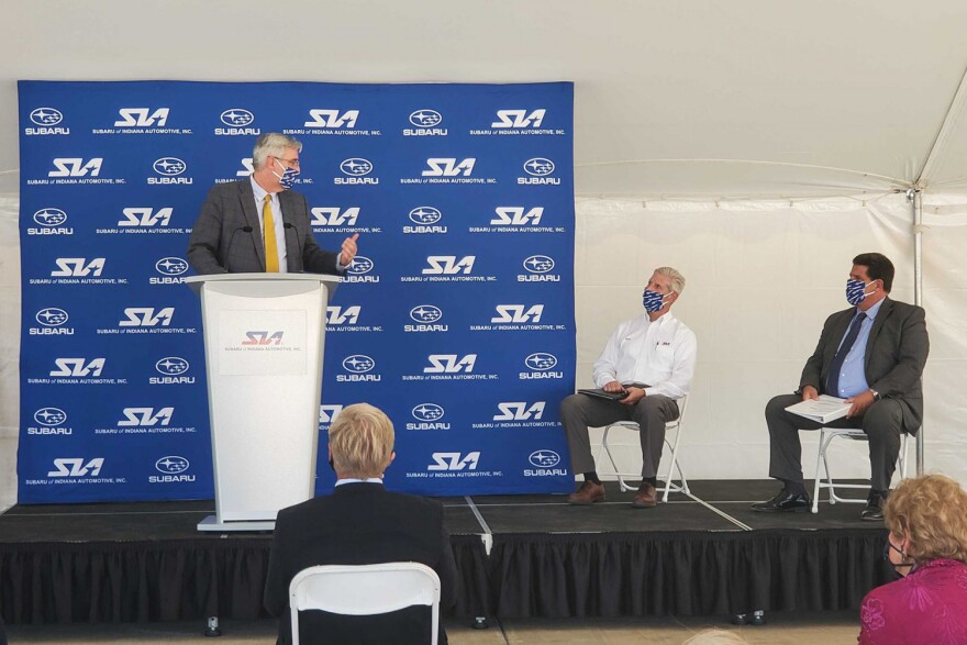 (Left to right) Gov. Eric Holcomb speaks at Subaru of Indiana Automotive ground breaking with SIA Vice President Scott Brand and Lafayette Mayor Tony Roswarski sitting on stage.