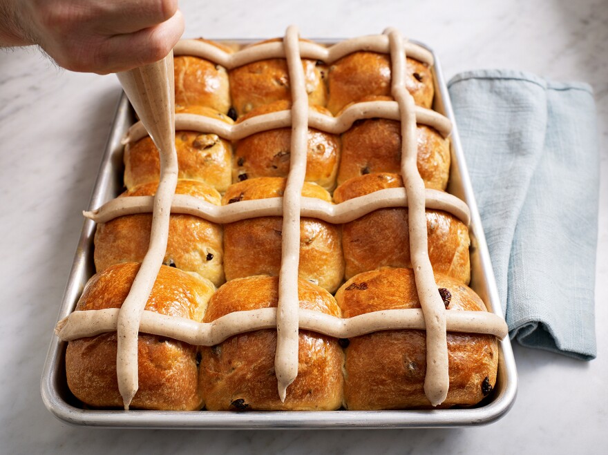 The <em>Bouchon</em> <em>Bakery<strong></strong></em> cookbook demonstrates how to apply the frosting "cross" on a pan of hot cross buns.