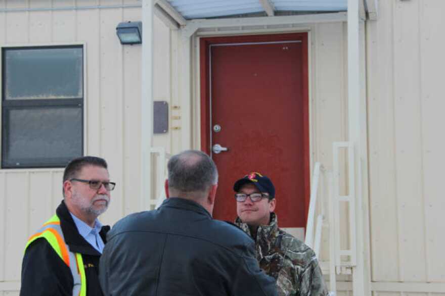 From left, Darryl Parks, chief of operations in civil engineering at JBER; Bob Sherrill of the Defense Logistics Agency; and Newtok Tribal Administrator Andrew John stand in front of one of the barracks units. (Photo by Rachel Waldholz/Alaska’s Energy Desk)