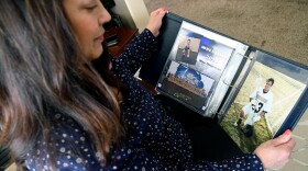 Kim Osterman holds a photo album with pictures of a young man.
