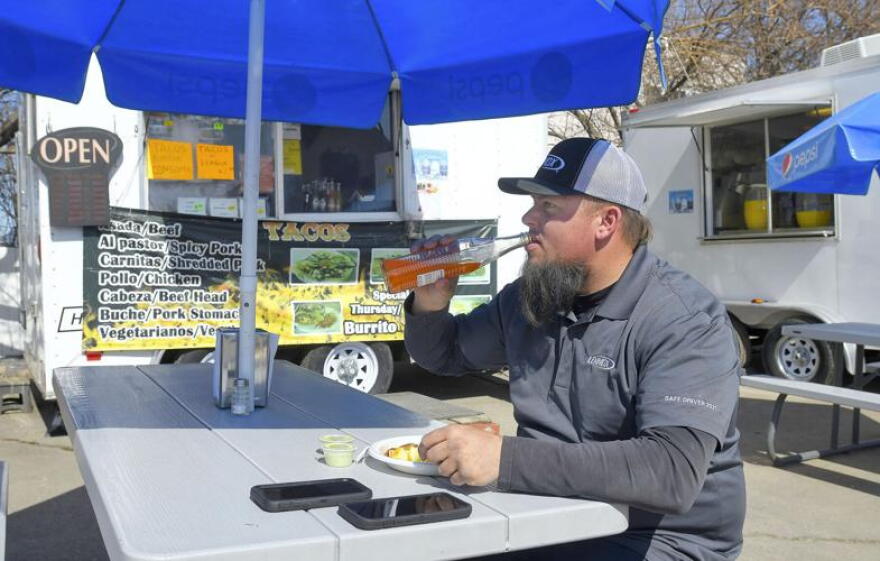 Trevor Rollins eats lunch at Down the Street Food Truck Park in Logan.