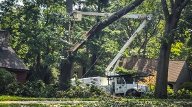 FILE- In this Aug. 7, 2020 file photo, workers clean up tree damage in Glastonbury, Conn. in the wake of Tropical Storm Isaias. Connecticut officials have announced an agreement with Eversource over the electric utility's problematic response to Tropical Storm Isaias, which left thousands of people without power for days. (AP Photo/David Collins, File)