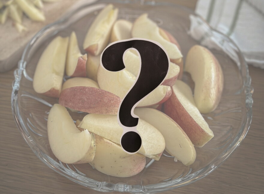 A bowl of sliced up apples; a question mark in the foreground