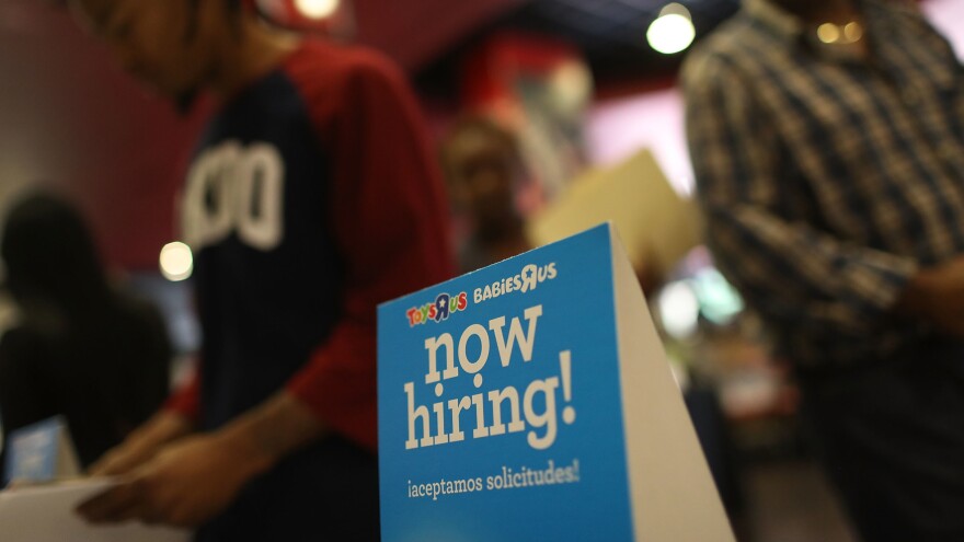 A "now hiring" sign is seen at the Toys R Us booth during the JobNewsUSA job fair at the BB&T Center in Sunrise, Fla., on Nov. 15.