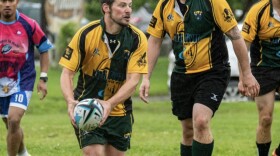 Dan Balmer, center, holds a ball during a rugby match.