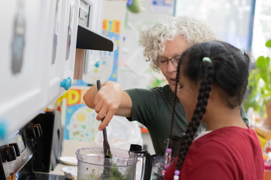 Global Gardens garden educator Mary Smith shows a student how to use a food processor at Tulsa Public Schools' Eugene Field Elementary. The students made a carrot top pesto spread with harvested greens from the after-school program's garden.
