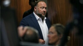 Alex Jones walks into the courtroom in front of Scarlett Lewis and Neil Heslin, the parents of 6-year-old Sandy Hook shooting victim Jesse Lewis, at the Travis County Courthouse in Austin in 2022.
