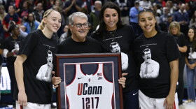 UConn head coach Geno Auriemma holds a jersey presented to him by players Paige Bueckers, left, Caroline Ducharme, and Azzi Fudd, right, as he is honored for the most wins in college basketball history, Wednesday, Nov. 20, 2024, in Storrs, Conn. (AP Photo/Jessica Hill)