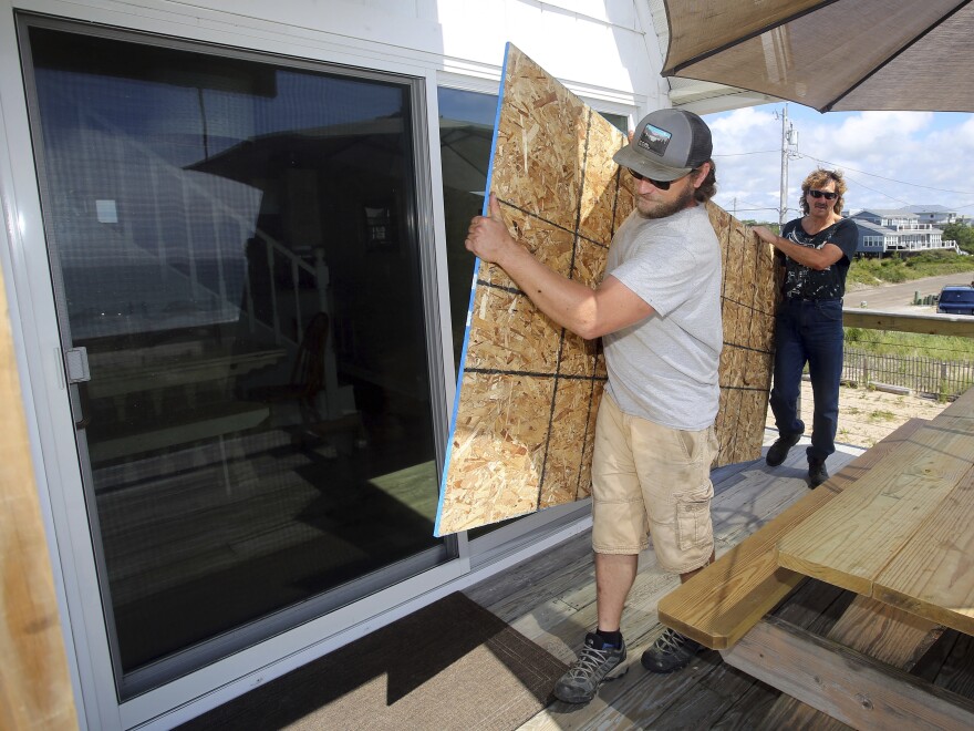 James Masog (center) and Gary Tavares prepare to board up a house Saturday in Charlestown, R.I., ahead of Hurricane Henri.