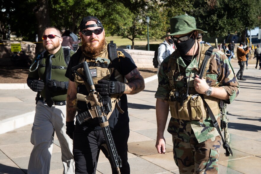 Kris Hunter (center) and two other armed protesters join a small rally outside of the state Capitol grounds on Sunday.