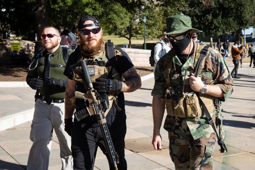 Kris Hunter (center) and two other armed protesters join a small rally outside of the state Capitol grounds on Sunday. 