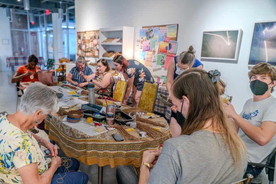 Basket Coiling Workshop led by Solarpunk Surf Club member Alyssum Pohl on Aug 4, 2024 in Bolivar Gallery. Participants are wrapping long-leaf pine needles and sewing with waxed cotton thread.