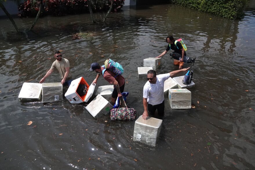 People try and save valuables as they wade through high flood waters in the Edgewood neighborhood of Fort Lauderdale south of State Road 84 just north of Fort Lauderdale-Hollywood International Airport on Thursday, April 13, 2023. South Florida was drenched by rain Wednesday causing major flooding and closing the airport.