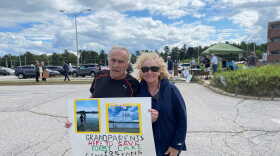 A man and woman hold a sign reading "Grandparents here to save forest lake for generations to come."