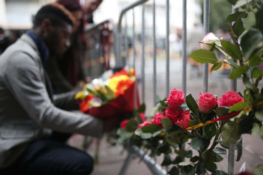 A man places flowers outside the scene of the fire.