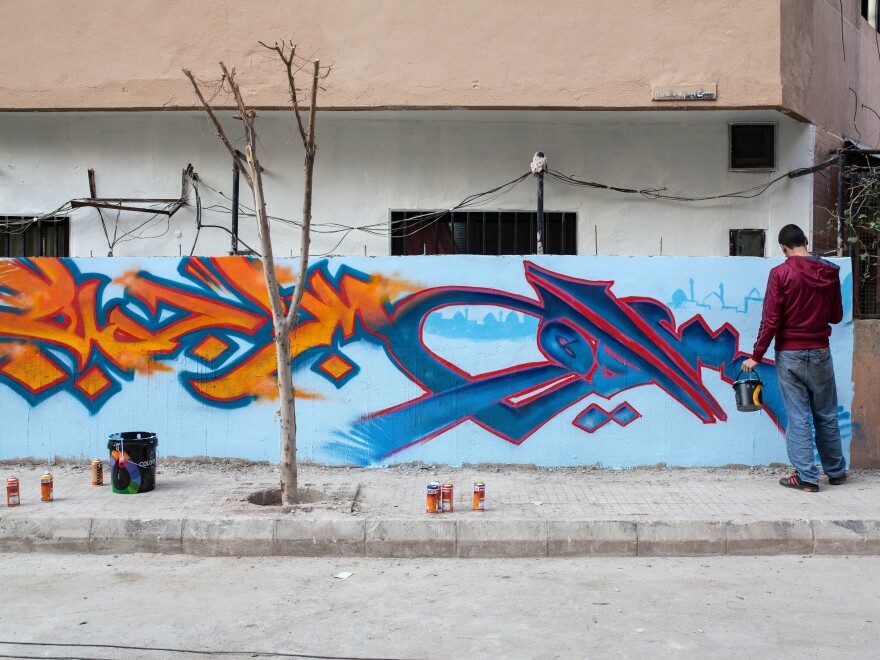 A man paints a mural that reads "patience is beautiful" in Arabic, near the site of a bombing in an area of Beirut, Lebanon known as the Dahiyeh.