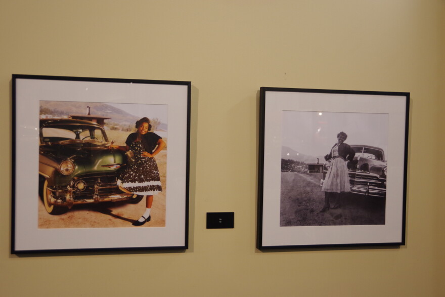 A woman in a black and white dress with white spots poses in front of a old dark green car from around the 1940s. Another photos hangs to the right, this time it's black and white, but the pose and car look much like the image on the left. 