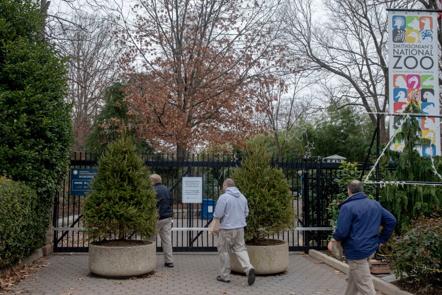 Zoo workers enter the Smithsonian National Zoo earlier this month. The main gate is closed to the public. The zoo is one of the many D.C. attractions that have been forced to close or scale back because of the shutdown.
