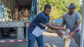 Jarvis Jones and John Knight help distribute free bottled water at the Sykes Park Community Center in Jackson, Mississippi.