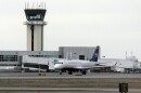 A passenger airplane taxis at an airport with jet bridges in the background 