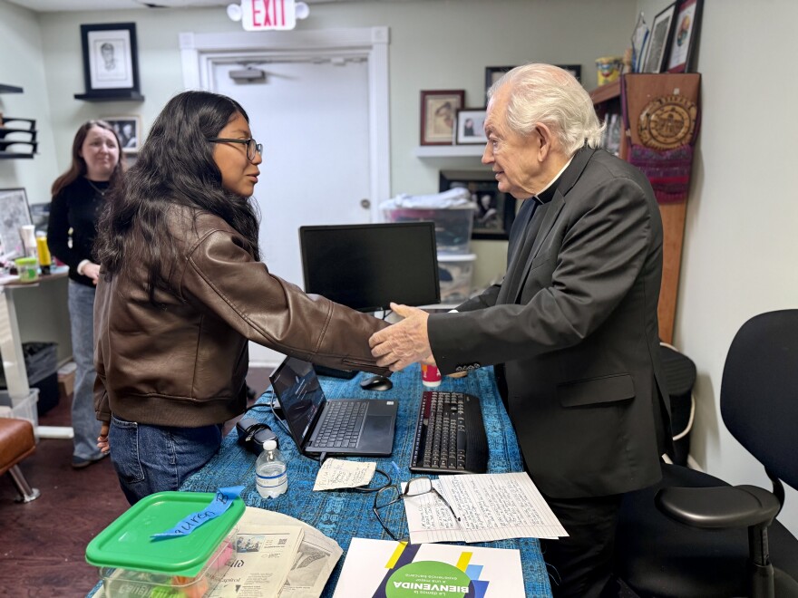 Eliza Perez (right), the daughter of respected community leader Olga Perez, shakes hands with Father Frank O’Loughlin, an Irish-born Roman Catholic priest, after an emotional prayer ahead of a scheduled online deportation hearing for Olga. | March 18, 2026