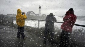 Visitors get splashed with sea spray while photographing Portland Head Light, Maine, during a powerful winter storm, Friday, Dec. 23, 2022, in Cape Elizabeth, Maine.