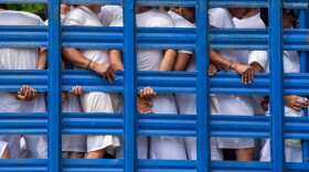 FILE - People detained by national police in the department of La Libertad stand in a truck as they are taken to a detention center in Soyapango, El Salvador, Oct. 7, 2022, during a state of the emergency.