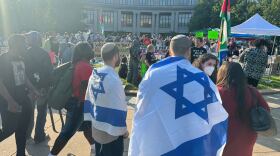 The flag of Israel is draped over the shoulders of two men watching demonstrators holding the Palestinian flag outside the library on the Case Western Reserve University campus.