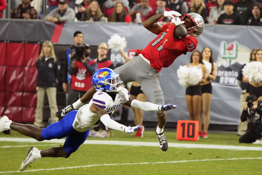 FILE - UNLV wide receiver Ricky White makes the catch over Kansas cornerback Cobee Bryant (2) during the second half of the Guaranteed Rate Bowl NCAA college football game Tuesday, Dec. 26, 2023, in Phoenix. (AP Photo/Rick Scuteri, File)