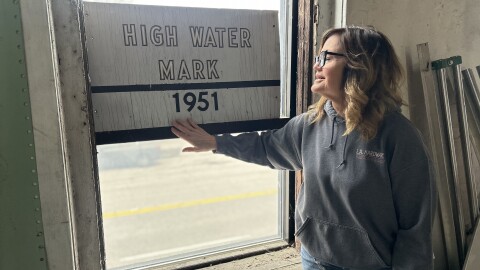 Shelly Eickhoff stands near a signpost on the second floor that marks the height of the 1951 flood.